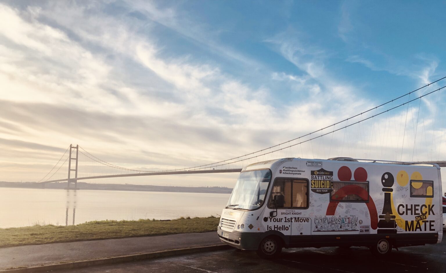 The 5asideCHESS Battle Bus parked at sunrise beside the Humber Bridge